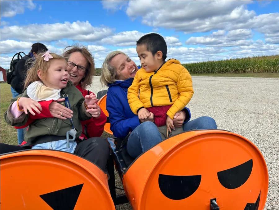 Therapists with students riding a pumpkin-themed cart at a farm outing