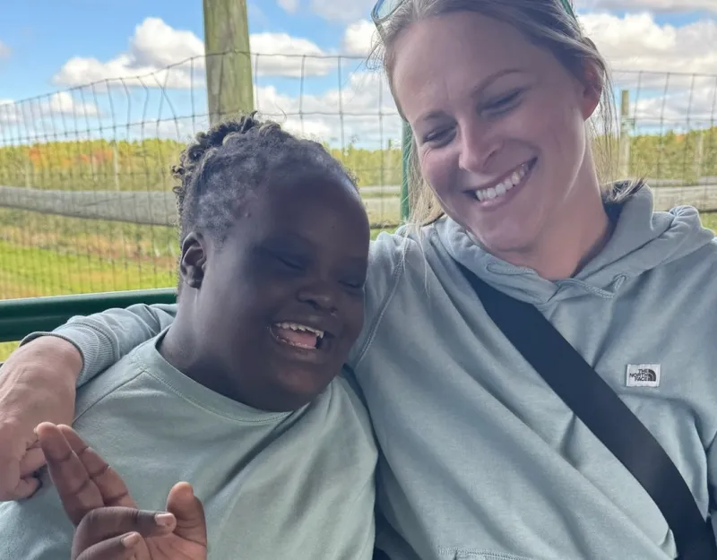 A staff member and student smiling together outdoors